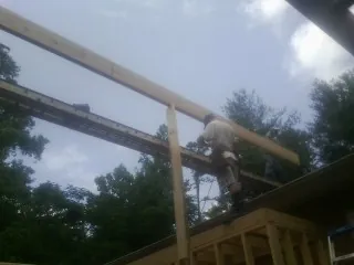 Carpenter setting a ridge beam over a new addition frame — Ice Dam Removal by Roofing Brothers in Yoakum