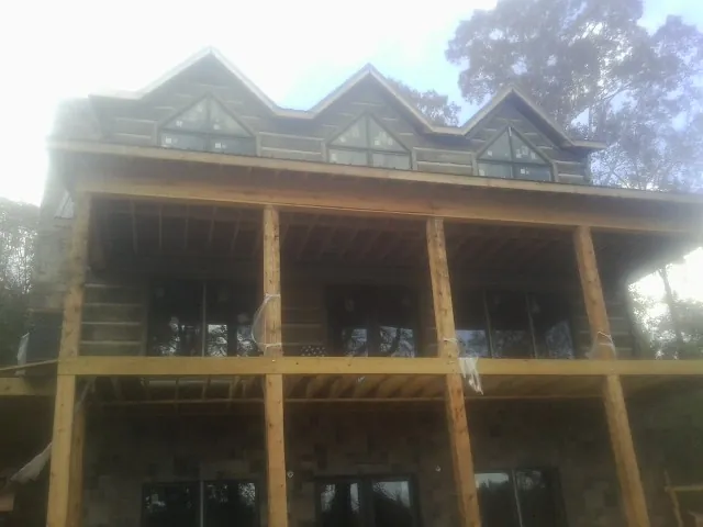 Dormers and porch framing on a large log home under construction — Roof Coating work by our crew in Yoakum