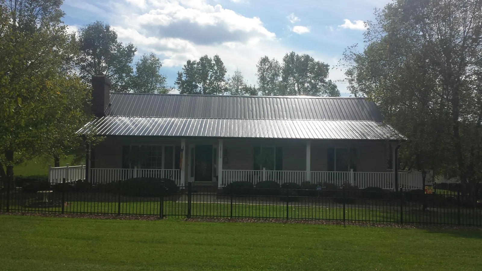 Gray metal roof on a brick ranch with a full width front porch — Gutter Guard Installation work by our crew in Yoakum
