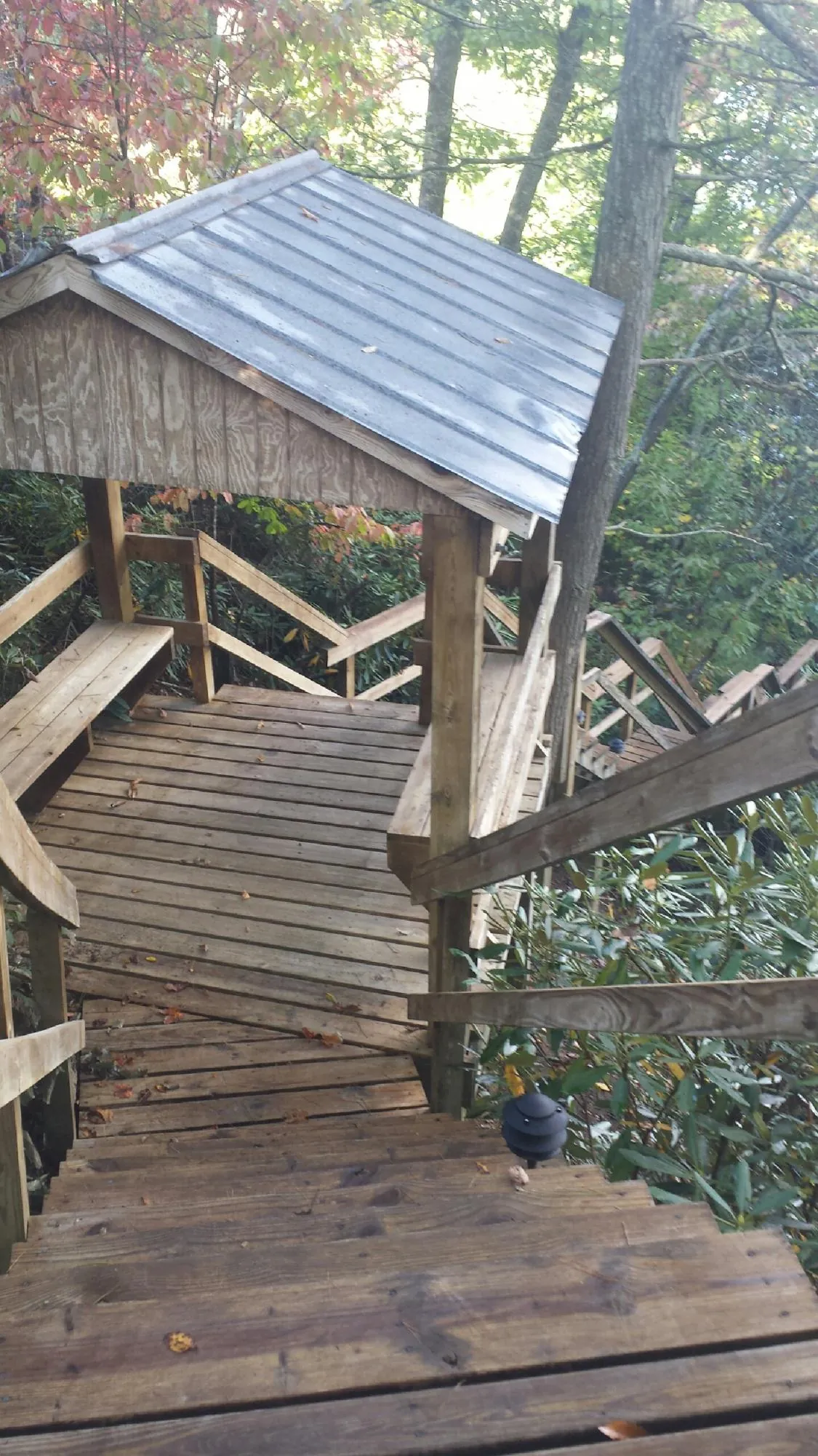 Metal roofed shelter over wooden steps on a wooded walkway — Skylight Repair & Installation work by our crew in Yoakum