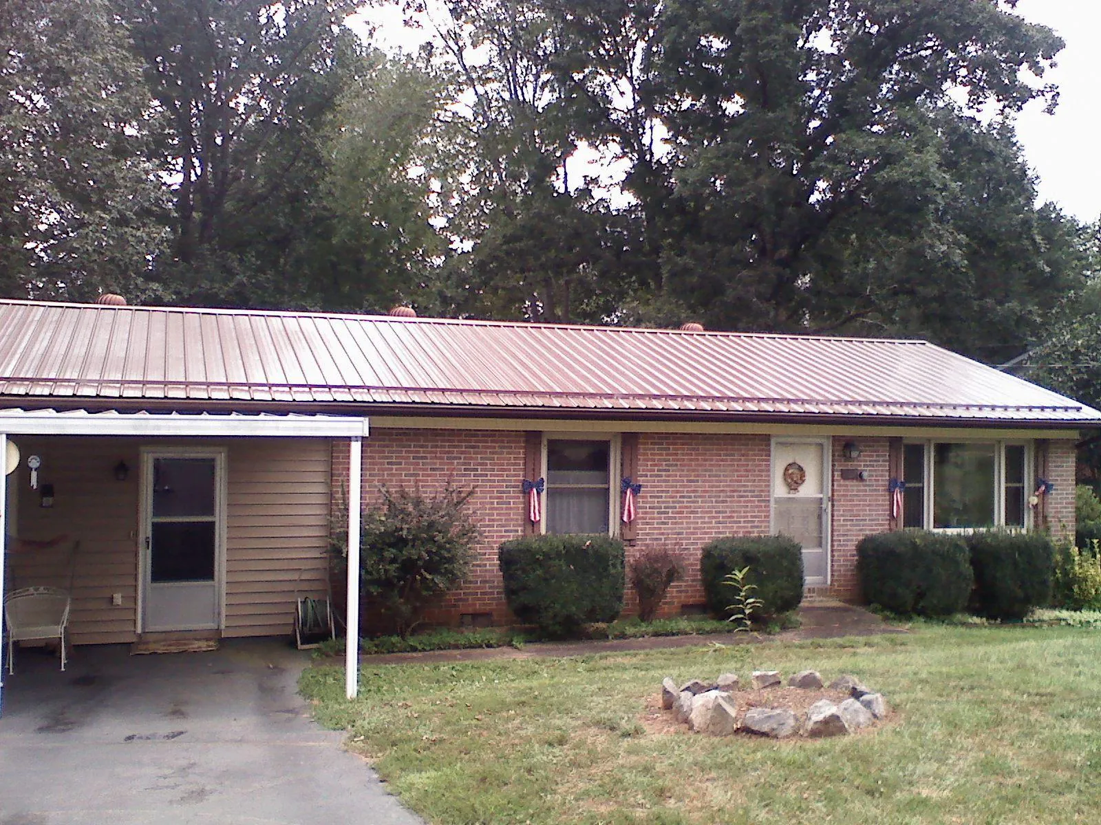 Bronze metal roof and carport on a brick ranch home — Roof Repair work by our crew in Yoakum