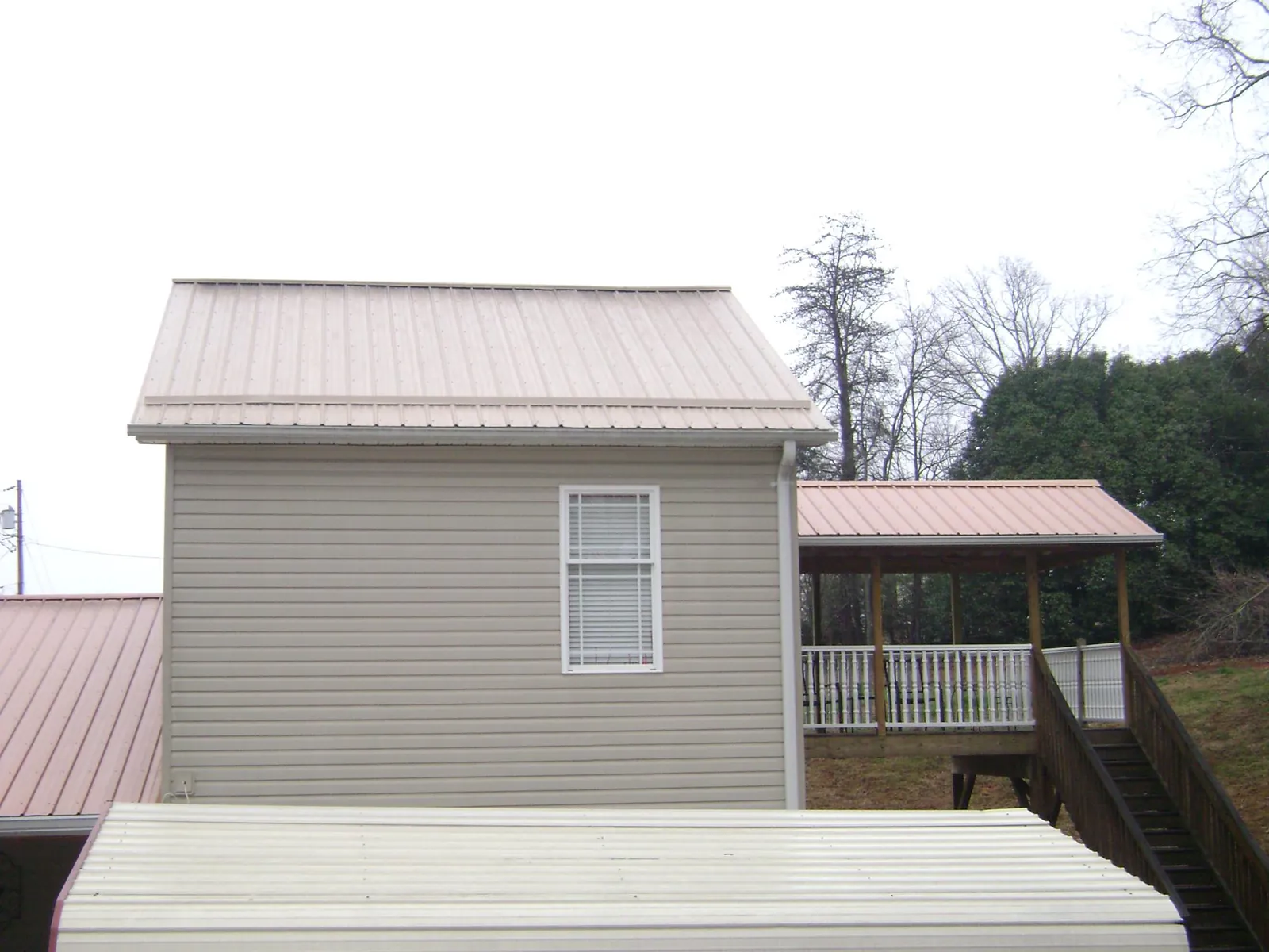 Tan metal roofs on a two story addition and attached porch, from a Roof Replacement job in Yoakum