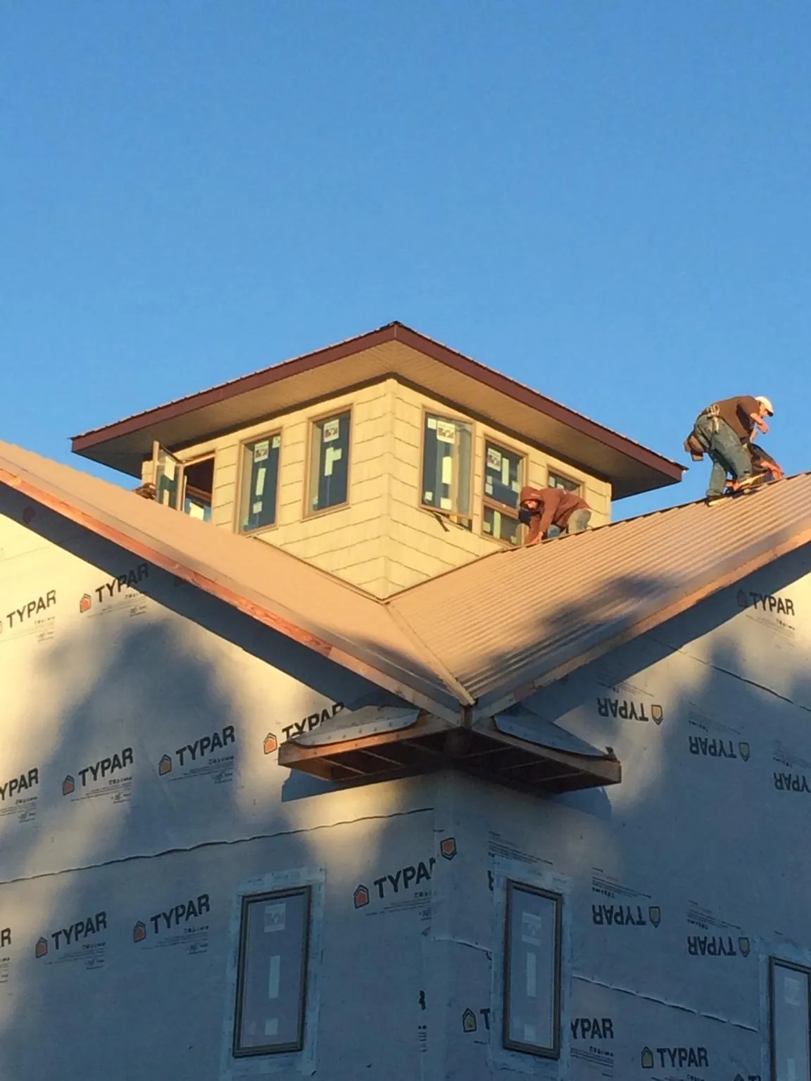 Roofers working around a rooftop cupola on a new metal roof at sunset — Roof Waterproofing in Yoakum by Roofing Brothers